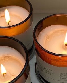 three lit candles sitting next to each other on top of a stove burner,