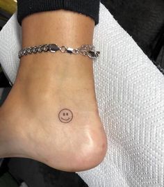 a woman's foot with a smiley face tattoo on the side of her ankle