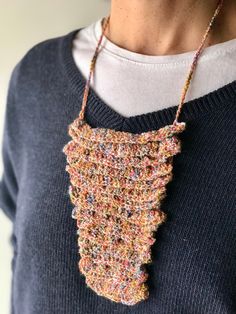 a woman wearing a knitted necklace with beads