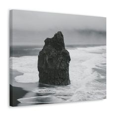 a rock sticking out of the ocean on a foggy day