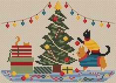 a cross stitch christmas tree with cats and presents on the bottom, hanging from a string