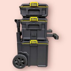 a black and yellow toolbox with wheels on a pink background that is cut out into the shape of a truck