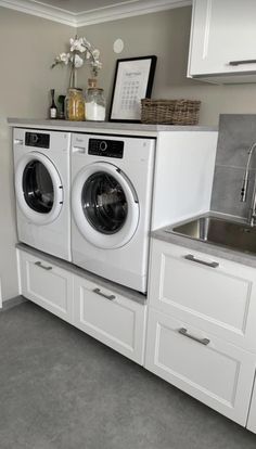 a washer and dryer sitting in a kitchen next to a counter with flowers on it