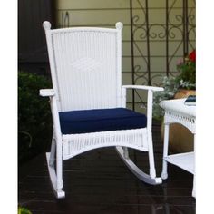 a white wicker rocking chair with blue cushion