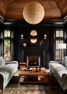 a living room with two couches and a table in front of a fire place