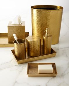 gold bathroom accessories including soap, toothbrush holder and tissue dispenser on marble countertop