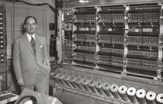 a man in a suit standing next to a machine with lots of buttons on it