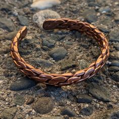 a close up of a bracelet on the ground with rocks and gravel in the background