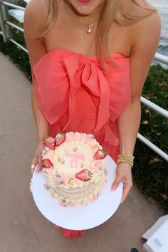 a woman is holding a cake on a plate