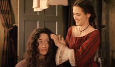 a woman is getting her hair done by another woman in front of an open door