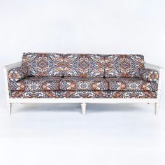 a couch with an orange, blue and white patterned upholstered design on it