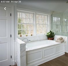 a large white bath tub sitting next to a window