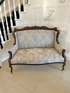 a couch sitting in the middle of a room next to a stair case and banister