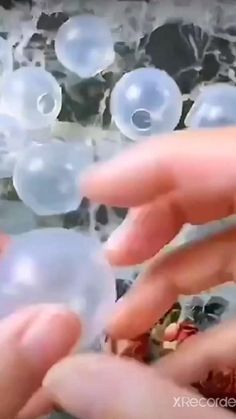 two hands reaching out to touch bubbles in the air with one hand and another hand holding an object