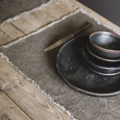 three black bowls are sitting on top of a wooden table with a knife and fork