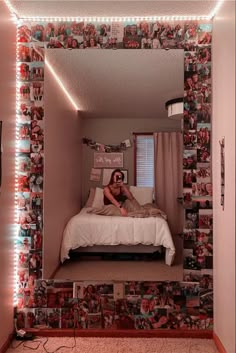 a woman sitting on top of a bed in front of a mirror with lights above it