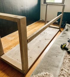 a wooden bench sitting on top of a hard wood floor next to a rug and window