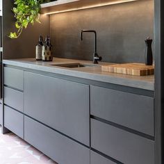 a kitchen with grey cabinets and plants on the counter top, along with a sink