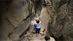 a woman is walking through the narrow rocks