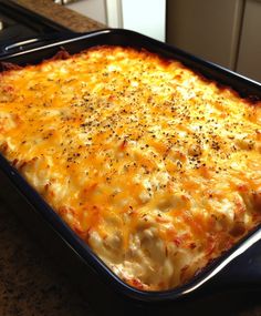 a casserole dish with cheese and seasoning on it sitting on a counter