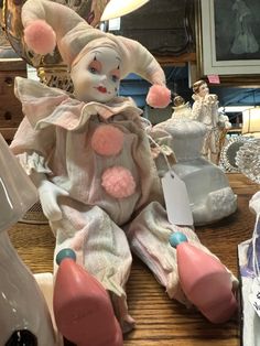 a creepy clown doll sitting on top of a wooden table next to other toys and decorations