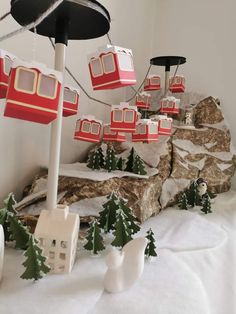 a table topped with snow covered trees and miniature red trams on top of rocks