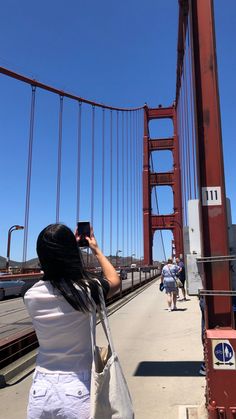 a woman taking a photo of the golden gate bridge