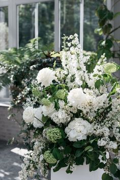 a white vase filled with lots of white flowers