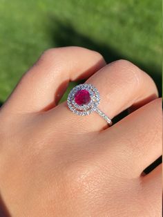 The Titania Double Halo Ruby and Diamond Ring in 14 Karat White Gold. This contemporary cocktail ring centers on a 1.05 carat ruby. The ruby is encircled by a double diamond halo with diamonds continuing down either side of the shank. The mounting has 0.58 total carats of diamonds. This modern ring is a finger size 6 3/4, yet can be adjusted to any size. Each piece has been hand selected and meticulously identified and graded by a Graduate Gemologist who has been awarded a degree by the Gemologi Dazzling Gia Certified Ruby Ring, Red Cluster Diamond Ring With Brilliant Cut, Red Diamond Cluster Ring With Halo Setting, Gia Certified Round Cut Ruby Ring Fine Jewelry, Ruby Ring With Diamond Cluster And Brilliant Cut, Cluster Ruby Ring With Brilliant Cut Diamonds, Gia Certified Round Cut Ruby Ring, Ruby Ring With Brilliant Cut Diamond, Formal Lab-created Ruby Ring With Halo Setting