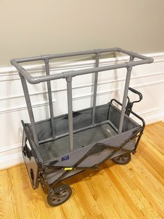 a gray cart sitting on top of a hard wood floor next to a white wall