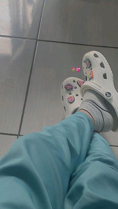 a person wearing crocs standing on a tile floor