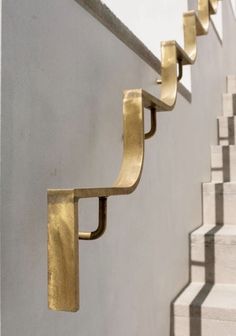 some metal brackets on the side of a wall next to stairs and cement steps with white walls