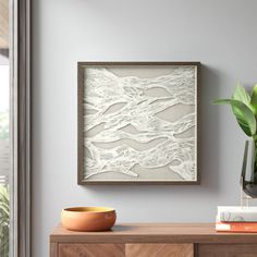 an abstract painting hangs on the wall next to a vase with a plant in it