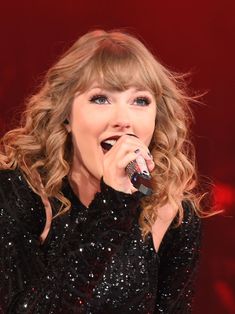 taylor swift singing into a microphone on stage