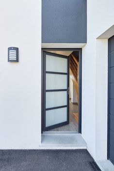 an open door to a white building with black trim on the front and side doors