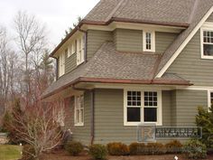 a gray house with brown shingles and white trim on the roof is shown in front of some trees