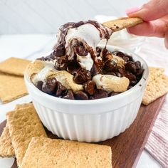 a person scooping ice cream into a bowl filled with chocolate chips and nuts,