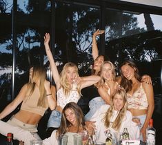 a group of women standing next to each other in front of a table with drinks on it