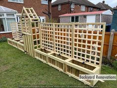 a wooden garden trellis sitting on top of a grass covered yard next to a house