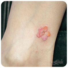 a small pink flower on the foot of a woman's left ankle, with an orange spot in the middle