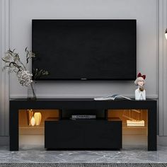 a flat screen tv mounted to the side of a wall next to a lamp and vase