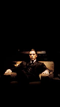 a man sitting on top of a couch in a dark room