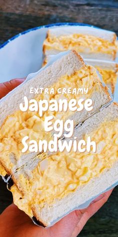 someone holding up a sandwich with eggs in it and the words extra creamy japanese egg sandwich