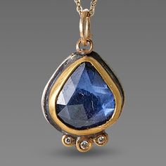 A stunning, deep blue, rose cut sapphire, wrapped in 22k gold shines with a trio of diamond accents, each set in a 22k gold dot. This lovely pendant is suspended from a 14k gold dot chain, with 14k lobster clasp. Setting measures approximately 3/8 inch x 1/2 inch. Sterling silver back. matte finish. Sapphire Jewelry With Single Cut Diamonds For Gift, Sapphire Jewelry With Single Cut Diamonds As A Gift, Blue Rose Cut Diamond Pendant Jewelry, Blue Rose Cut Diamond Pendant Necklace, Blue Pendant Necklaces With Rose Cut Diamonds, Sapphire Pendant With Single Cut Diamonds, Gold Teardrop Sapphire Necklace, Gold Teardrop Pendant With Rose Cut Diamonds, Unique Blue Jewelry With Rose Cut Diamonds