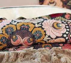 a close up of a pillow on top of a bed next to a fur rug