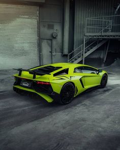 a bright yellow sports car parked in front of a garage door with stairs leading up to it