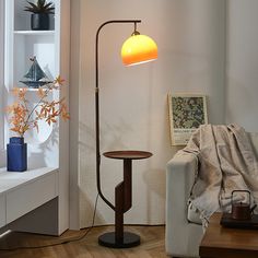 a living room with a couch, table lamp and bookshelf in the corner