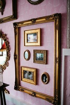 there are many pictures on the wall in this room with pink walls and gold frames