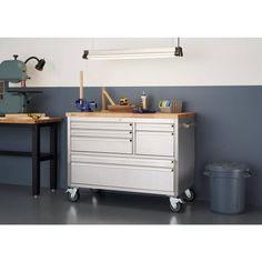 a workbench with drawers and tools on it in front of a blue wall