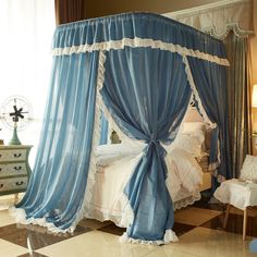 a canopy bed with blue drapes on top of it in a bedroom next to a dresser